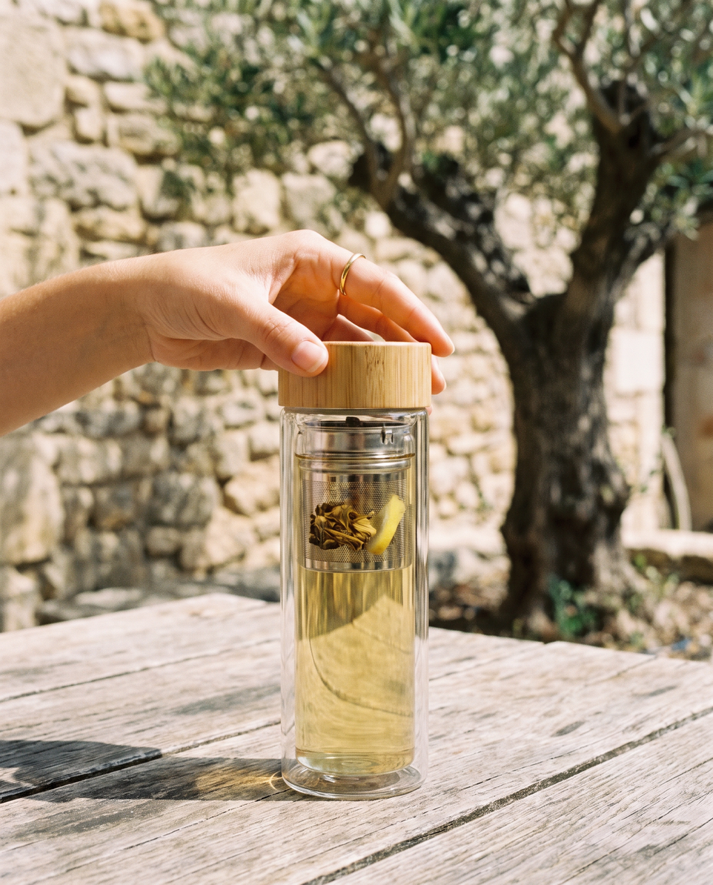 Gourde infuseur tenue en main sur une terrasse ensoleillée